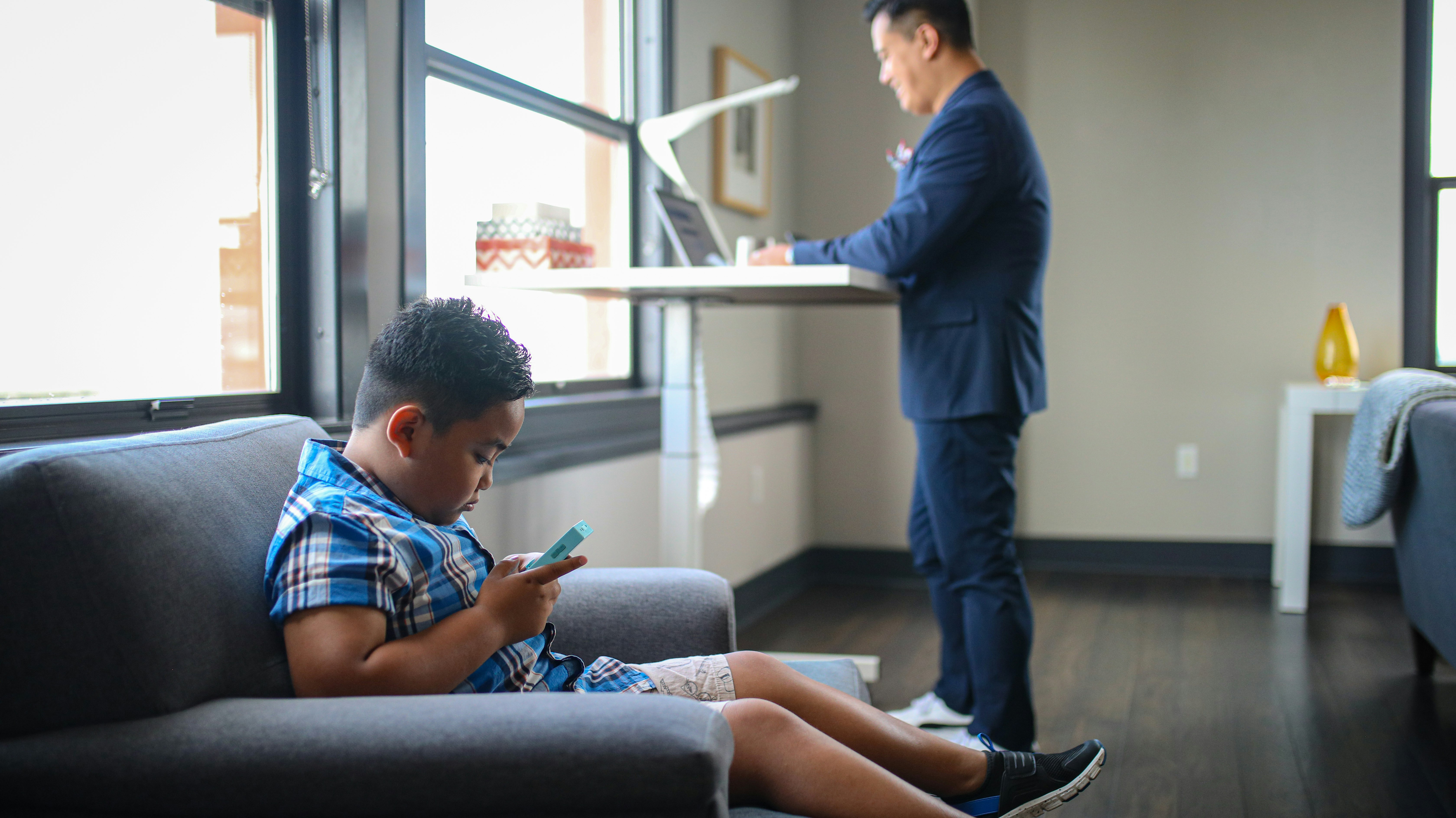 boy in blue and white plaid dress shirt sitting on gray couch